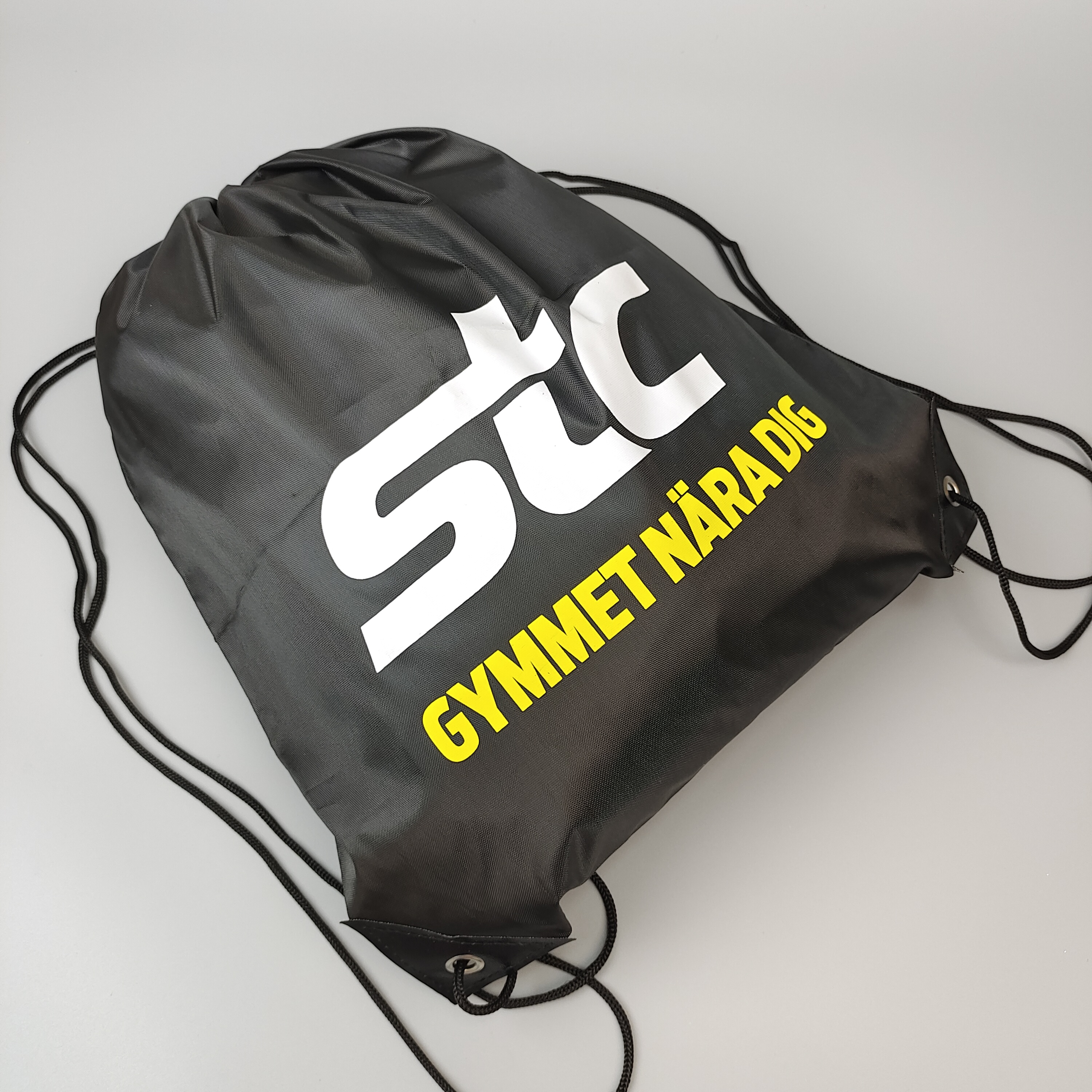 black polyester drawstring backpack with large white printed logo