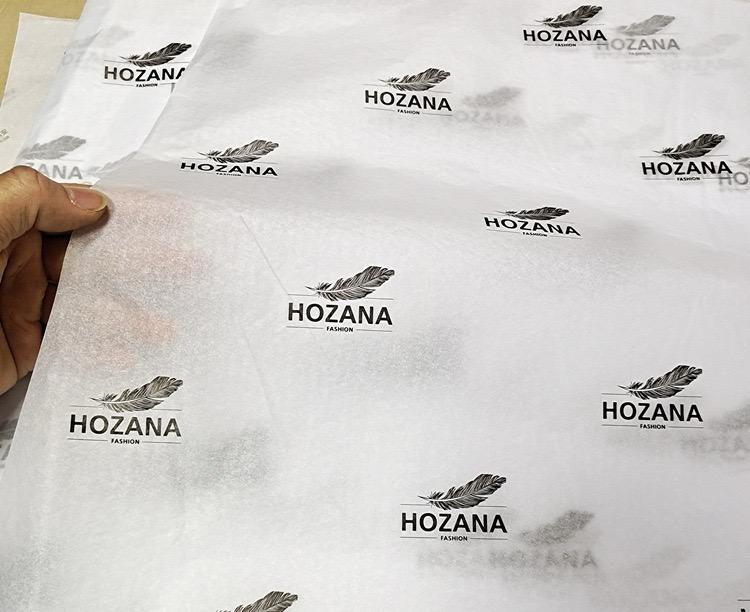white tissue paper with repeating black feather logo print - view 1