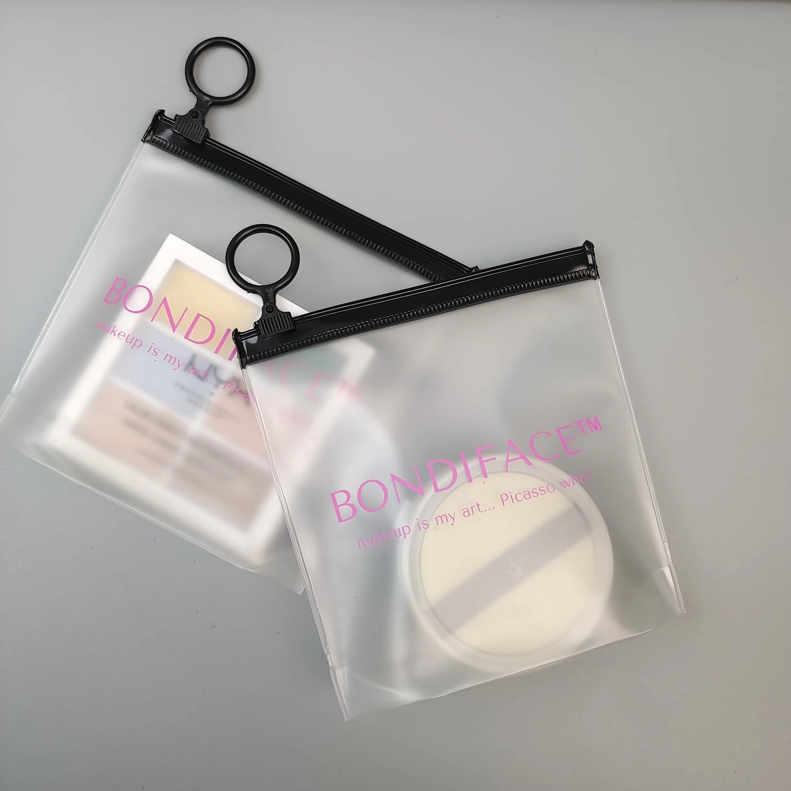 frosted PVC makeup pouches with pink logo and black ring pulls