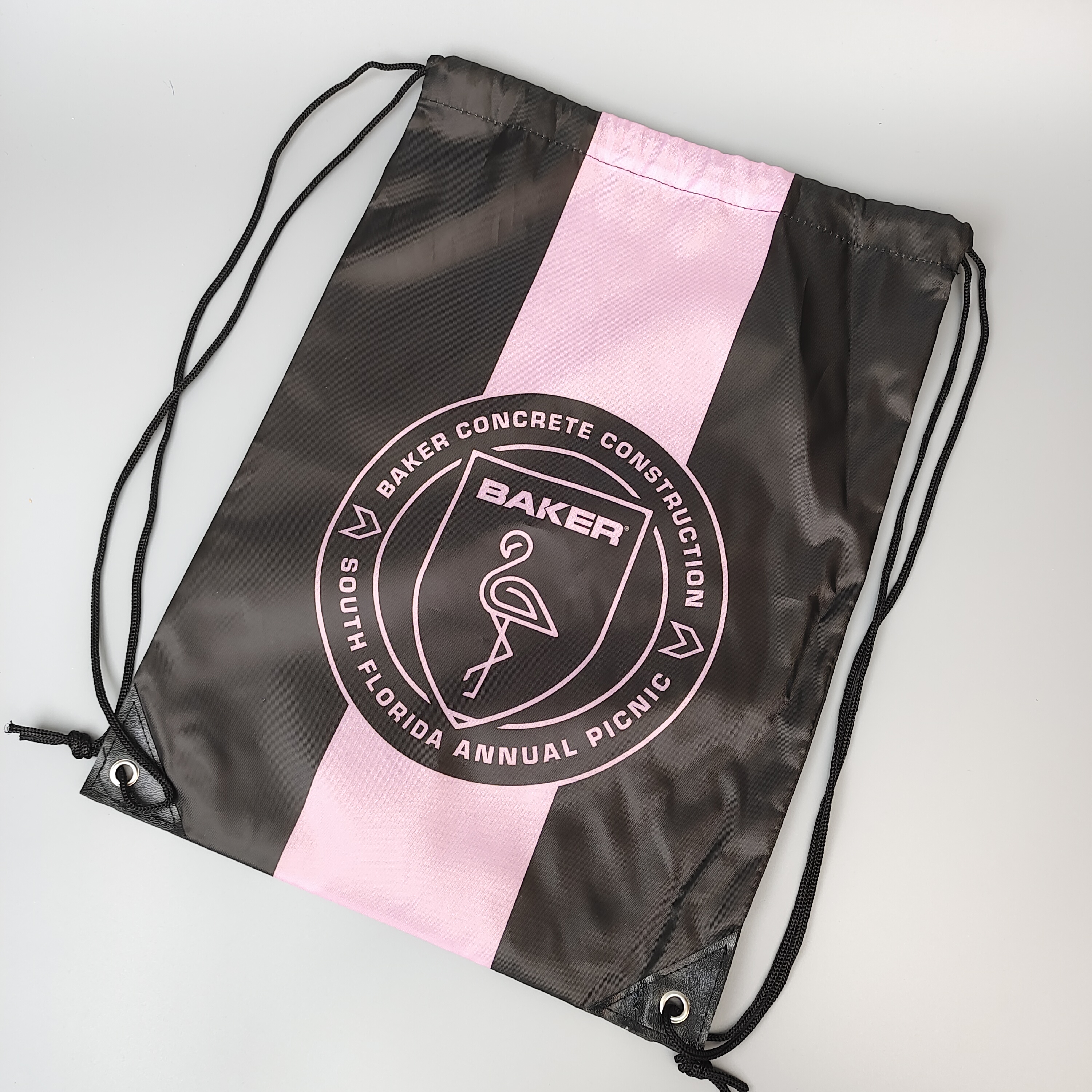 black polyester drawstring backpack with pink and white printed logo