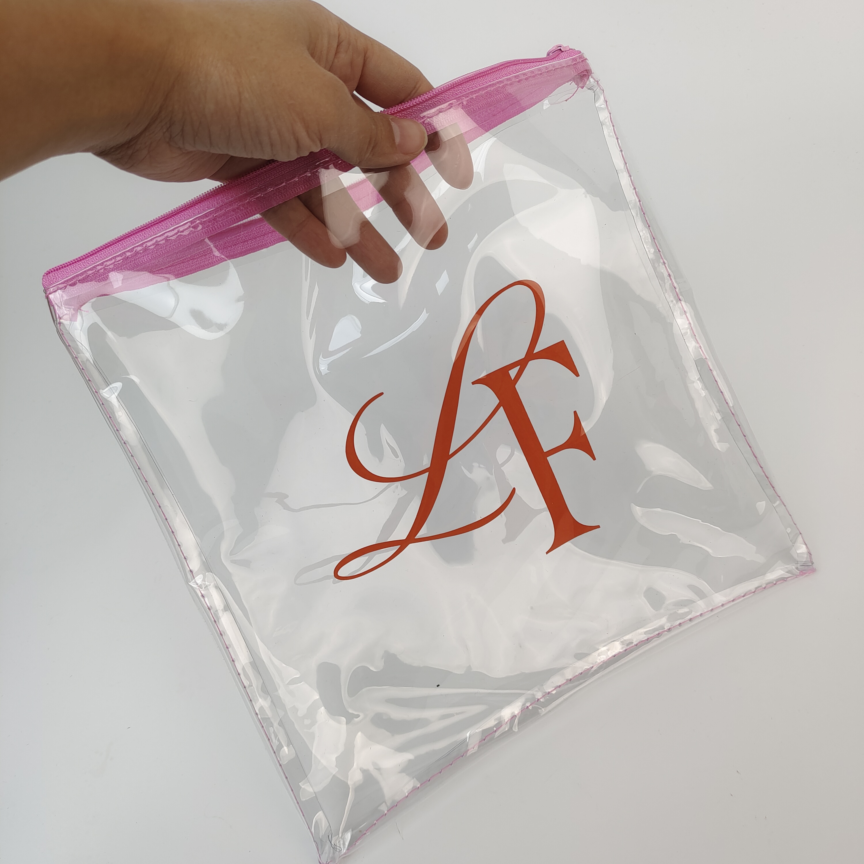 sewn clear PVC pouch with pink zipper and printed artwork