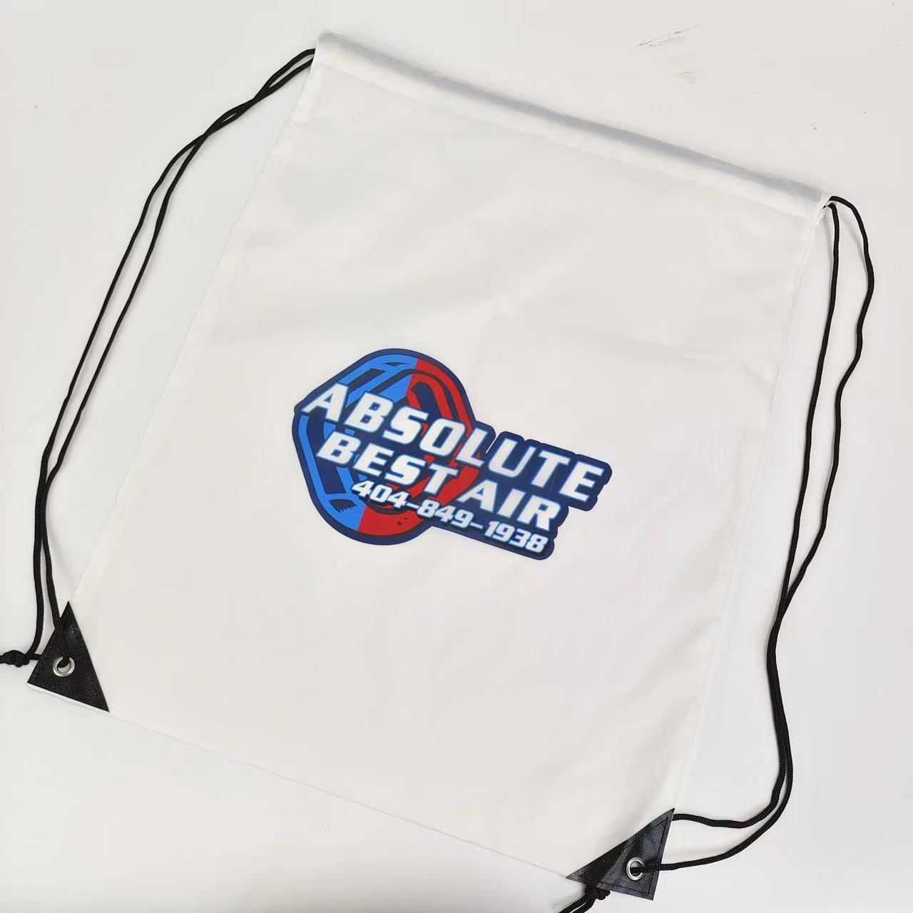 white promotional polyester drawstring bag with multicolor logo and black cords